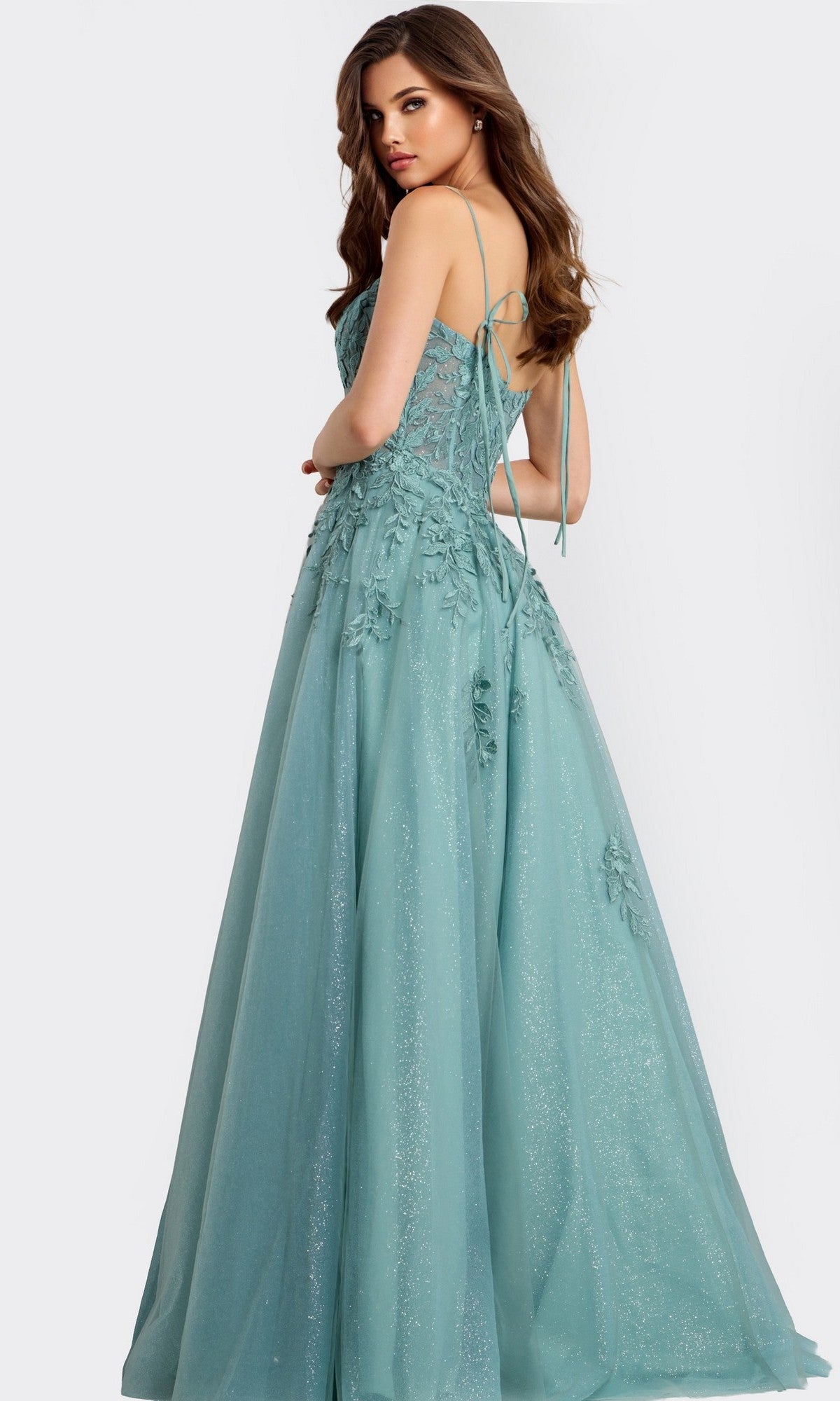 A woman models the Jovani 49092 long prom dress, featuring a floor-length, light teal sleeveless design with lace appliques, floral accents, and a glitter finish against a plain background.
